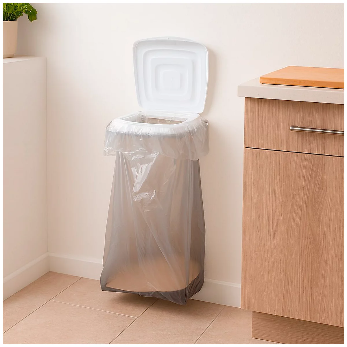 Une poubelle murale avec un couvercle ouvert et un sac en plastique à l'intérieur. À droite, un élément de cuisine.