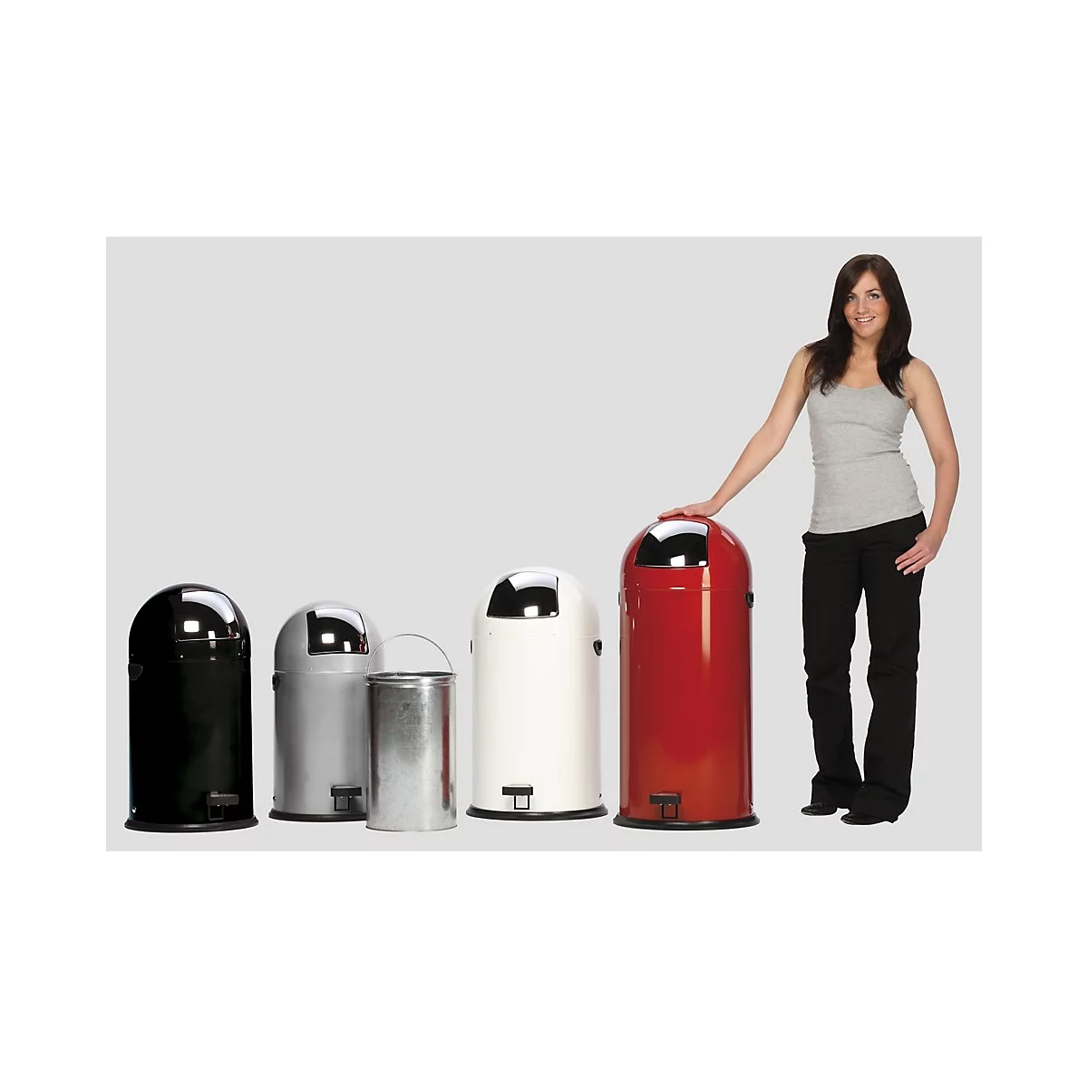 Femme à côté de poubelles de différentes couleurs. Elle touche la poubelle rouge.