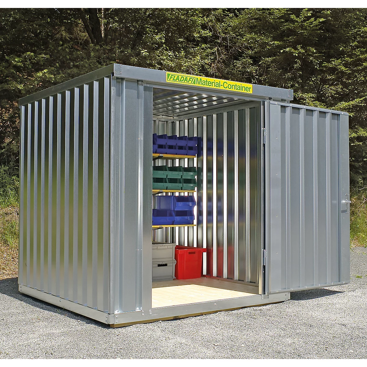 Grey metal container construction, open door. Inside shelves with blue and green boxes. Yellow lettering on the roof.