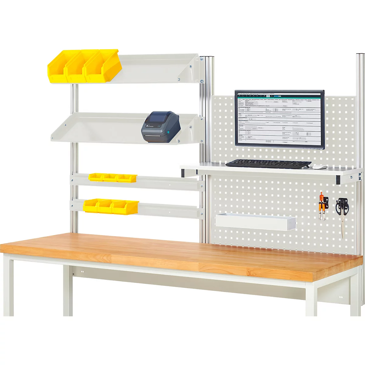 Établi avec outils, écran d'ordinateur et imprimante d'étiquettes. Des bacs jaunes et des étagères sont fixés à un mur blanc.