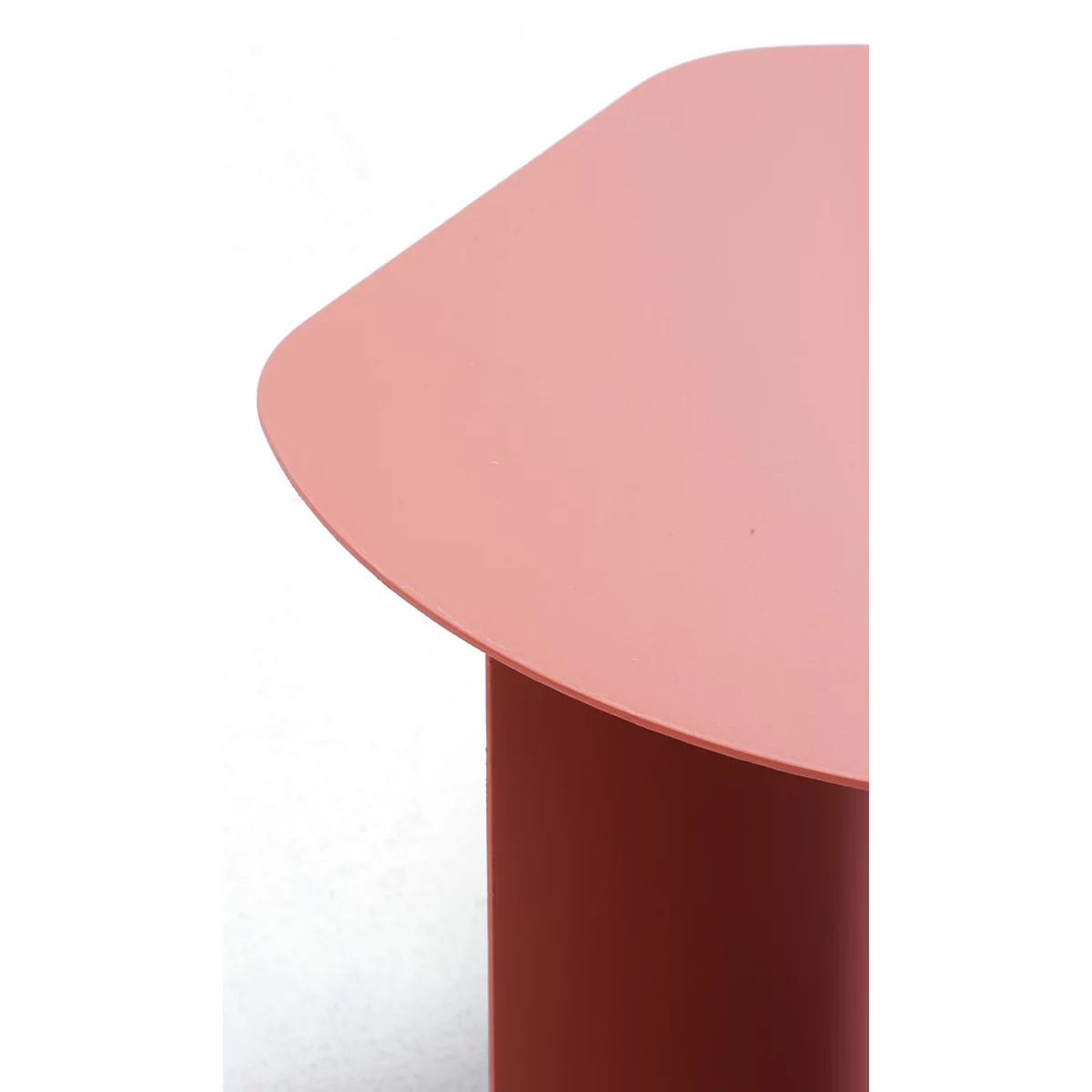 Gros plan sur un plateau de table incurvé, de couleur saumon, posé sur un pied cylindrique assorti.