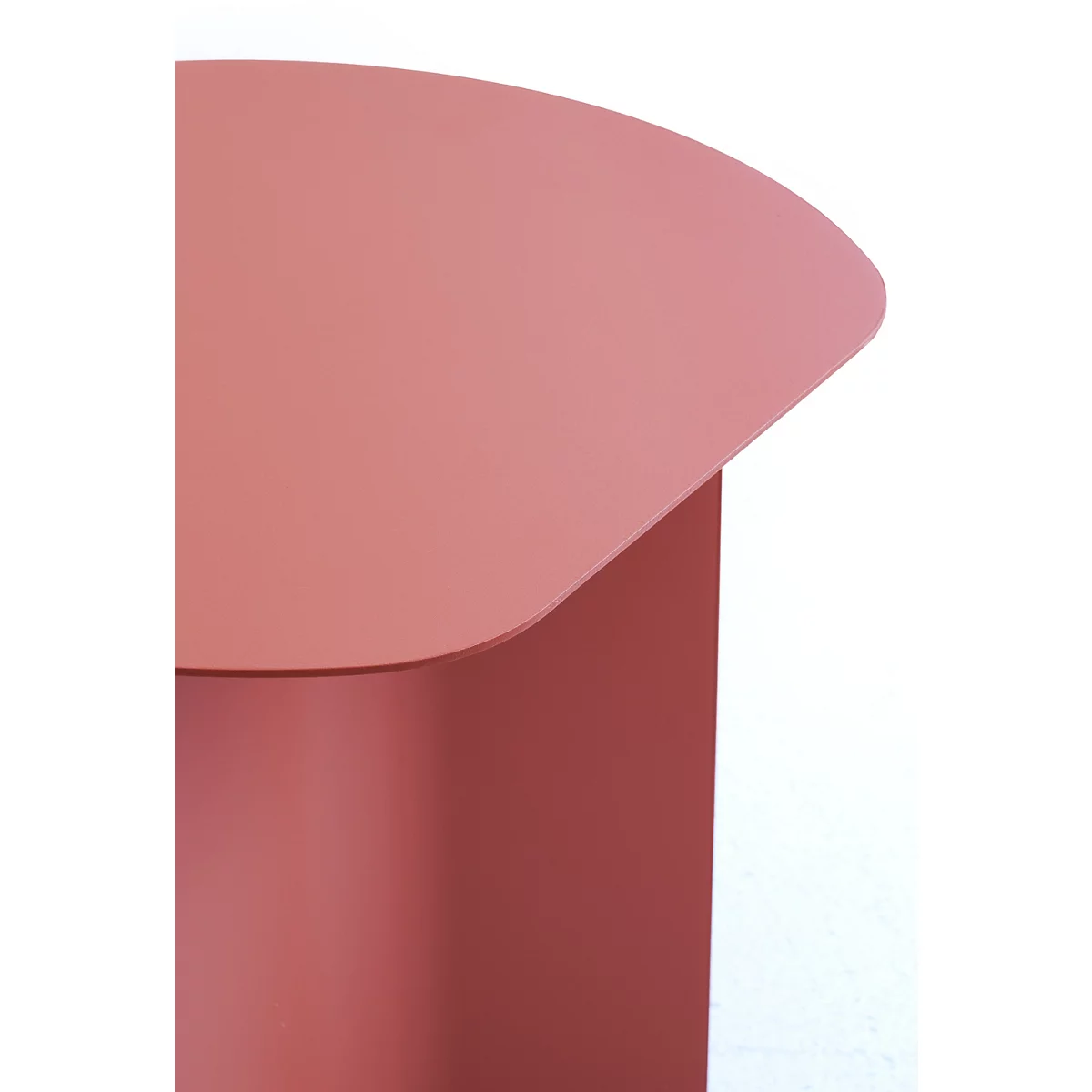 Gros plan sur un plateau de table arrondi couleur corail d'une table d'appoint en métal sur fond blanc.