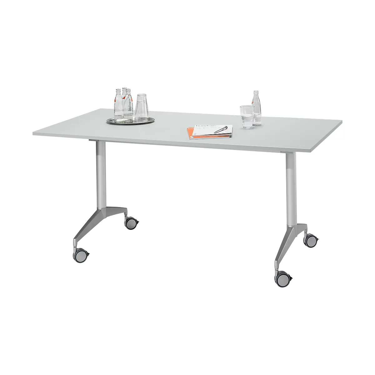 Une table rectangulaire blanche sur roulettes. Sur le plateau, des bouteilles d'eau, des verres et un bloc-notes.