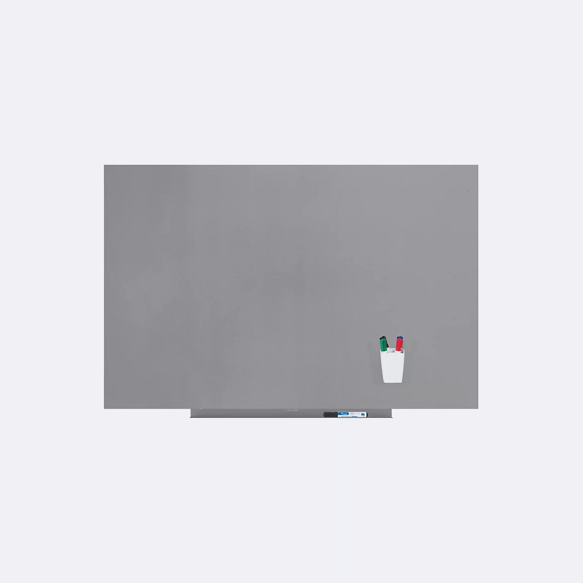 Tableau magnétique gris avec porte-stylos et stylos. Une étagère en dessous, à côté des stylos. Ambiance lumineuse.