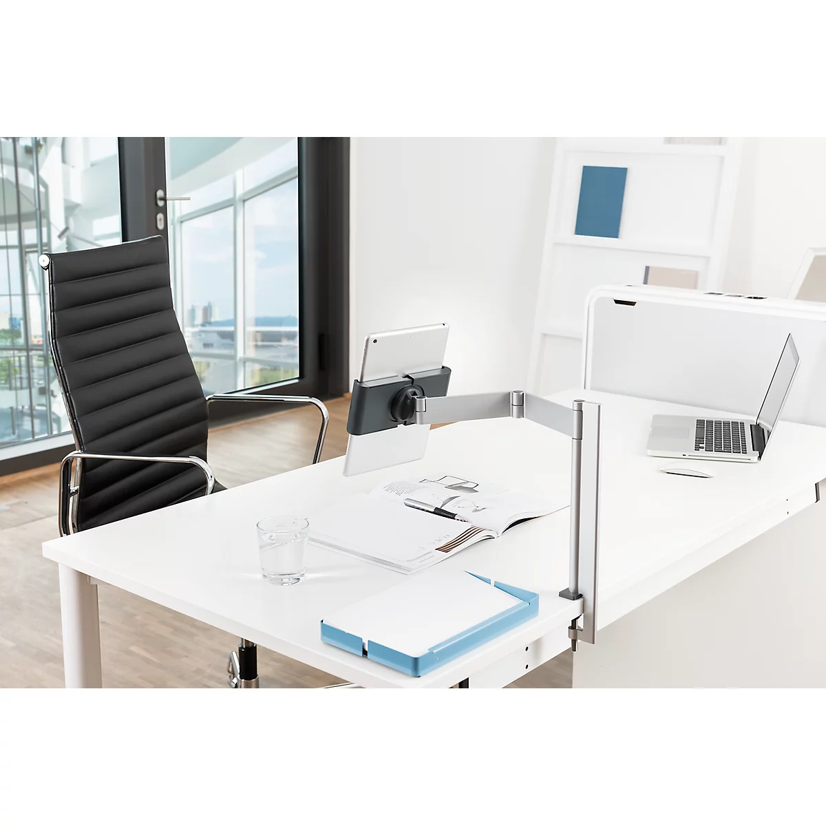 Desk with tablet holder, laptop, chair, and documents.