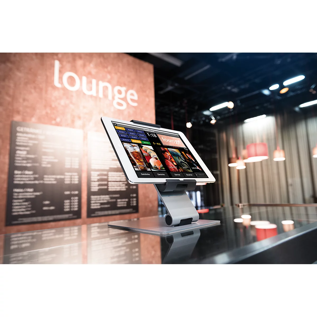 A tablet on a table displays menus. In the background, a sign reads "lounge."
