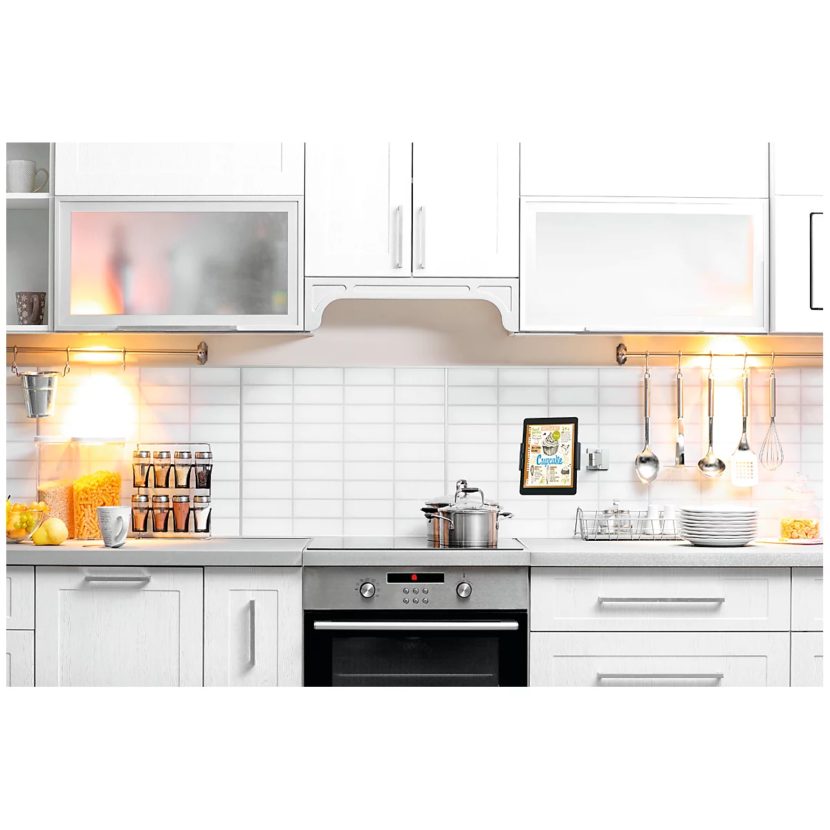 A modern white kitchen with stainless steel appliances and accessories.