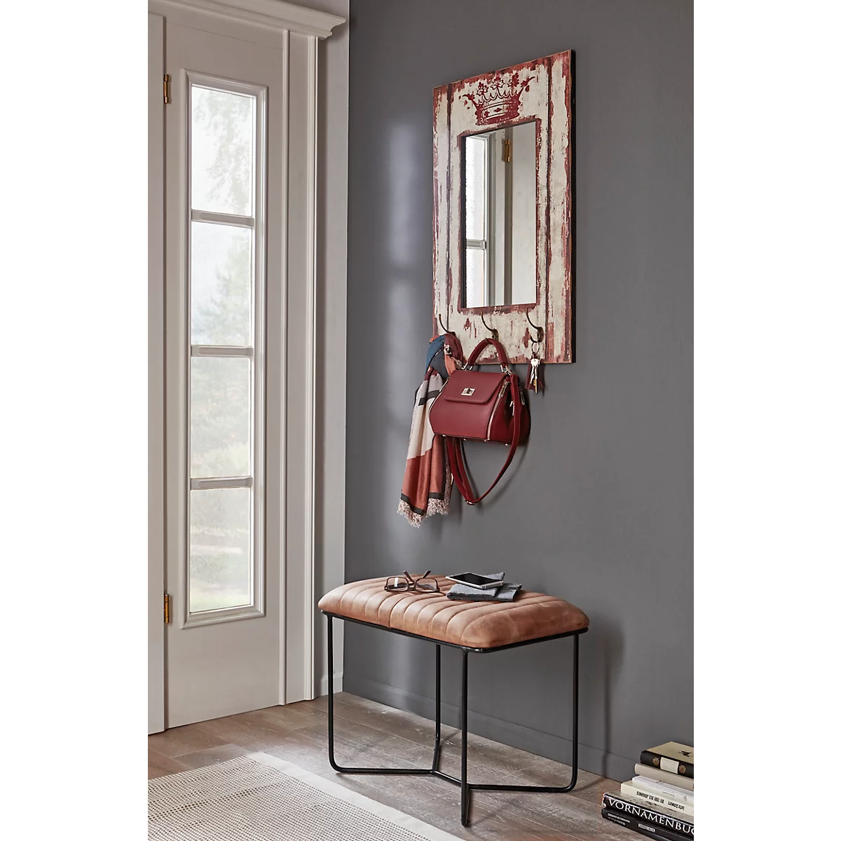 Un tabouret avec une assise marron et un cadre noir. Un petit objet repose sur le tabouret. A côté, une écharpe bleue. Il y a des chaussures par terre.
