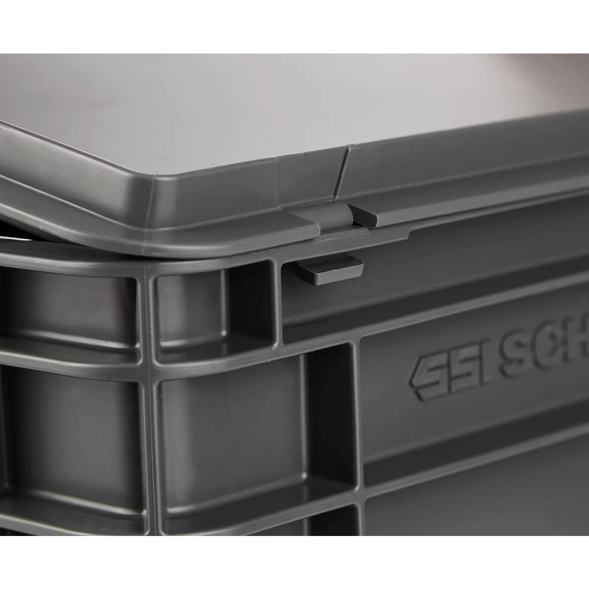 Caja de plástico gris, detalle del cierre. Tapa puesta, cierre bloqueado.