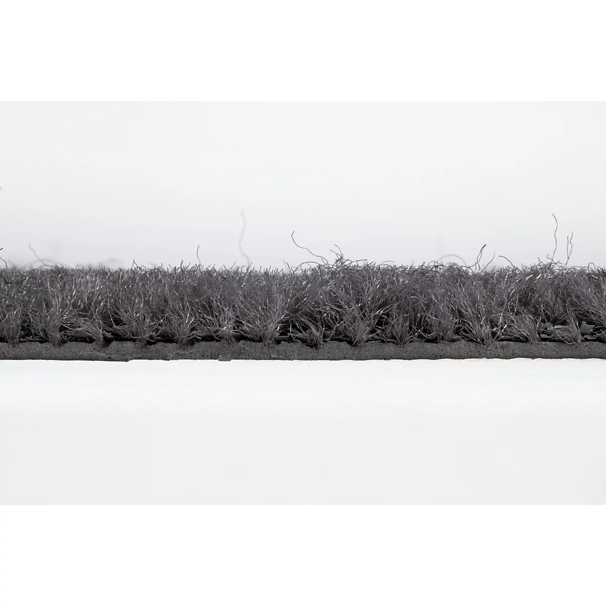 Gros plan sur un paillasson avec une bordure en caoutchouc noir et une surface textile grise.
