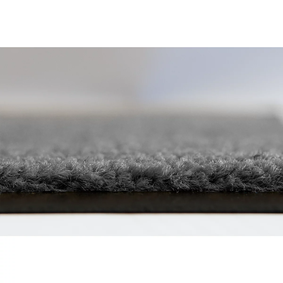 Gros plan sur une surface de tapis gris avec une structure de poils dense et texturée.