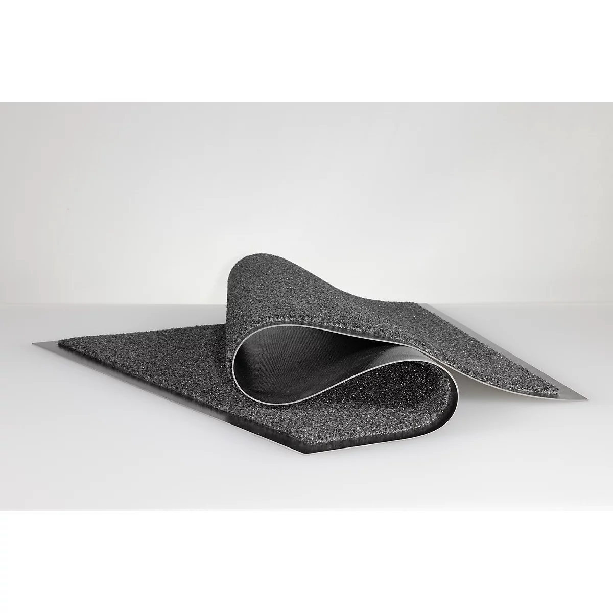 Un tapis d'entrée gris foncé enroulé avec un envers en caoutchouc sur un fond blanc.