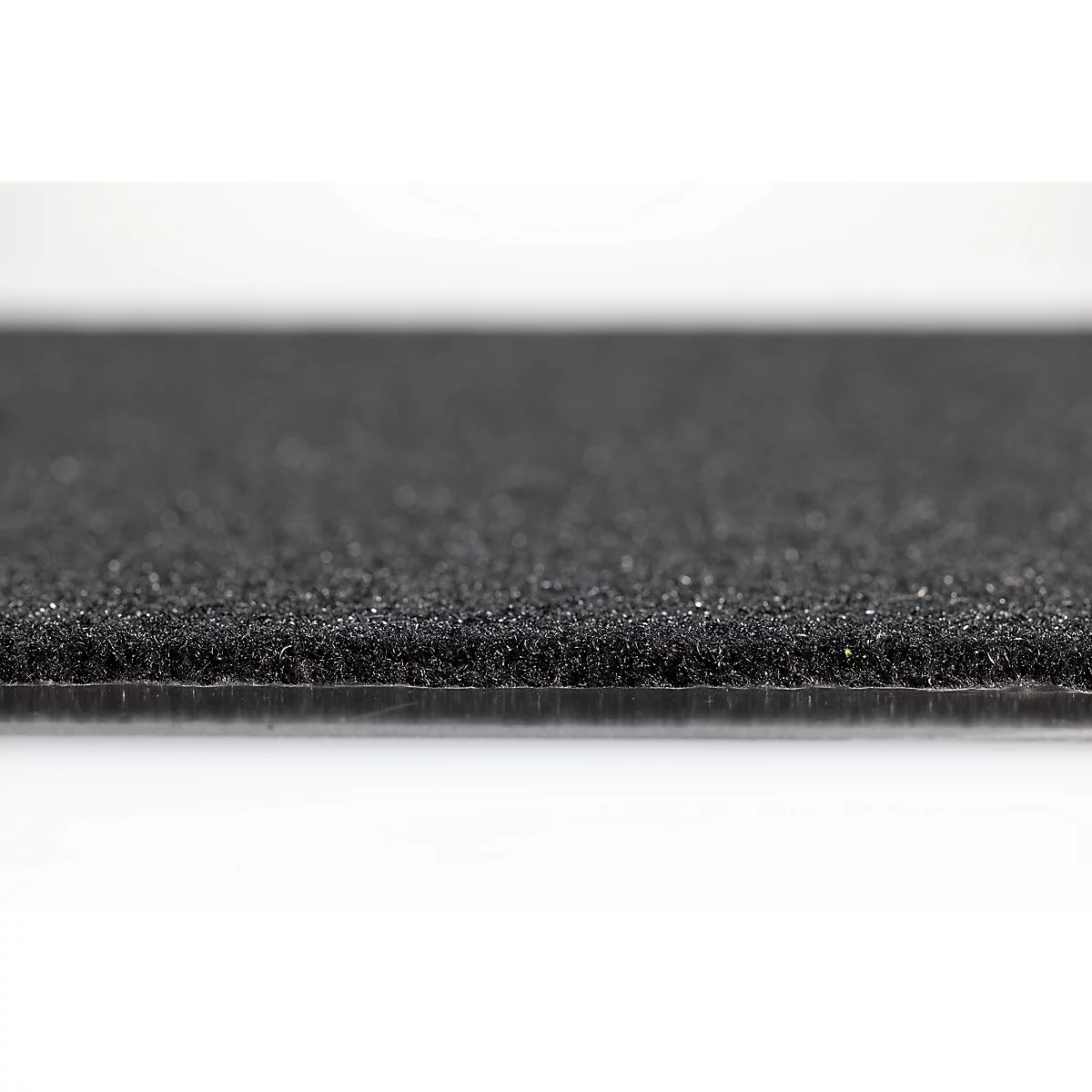 Gros plan sur un tapis en caoutchouc noir texturé ou un revêtement de sol à surface granuleuse.