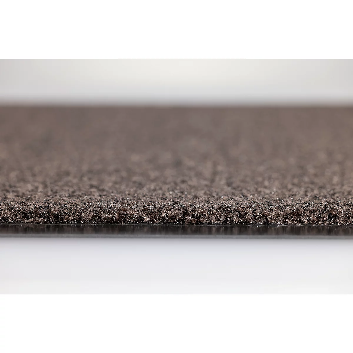 Gros plan sur la texture d'une moquette marron foncé vue de côté avec sous-couche visible.