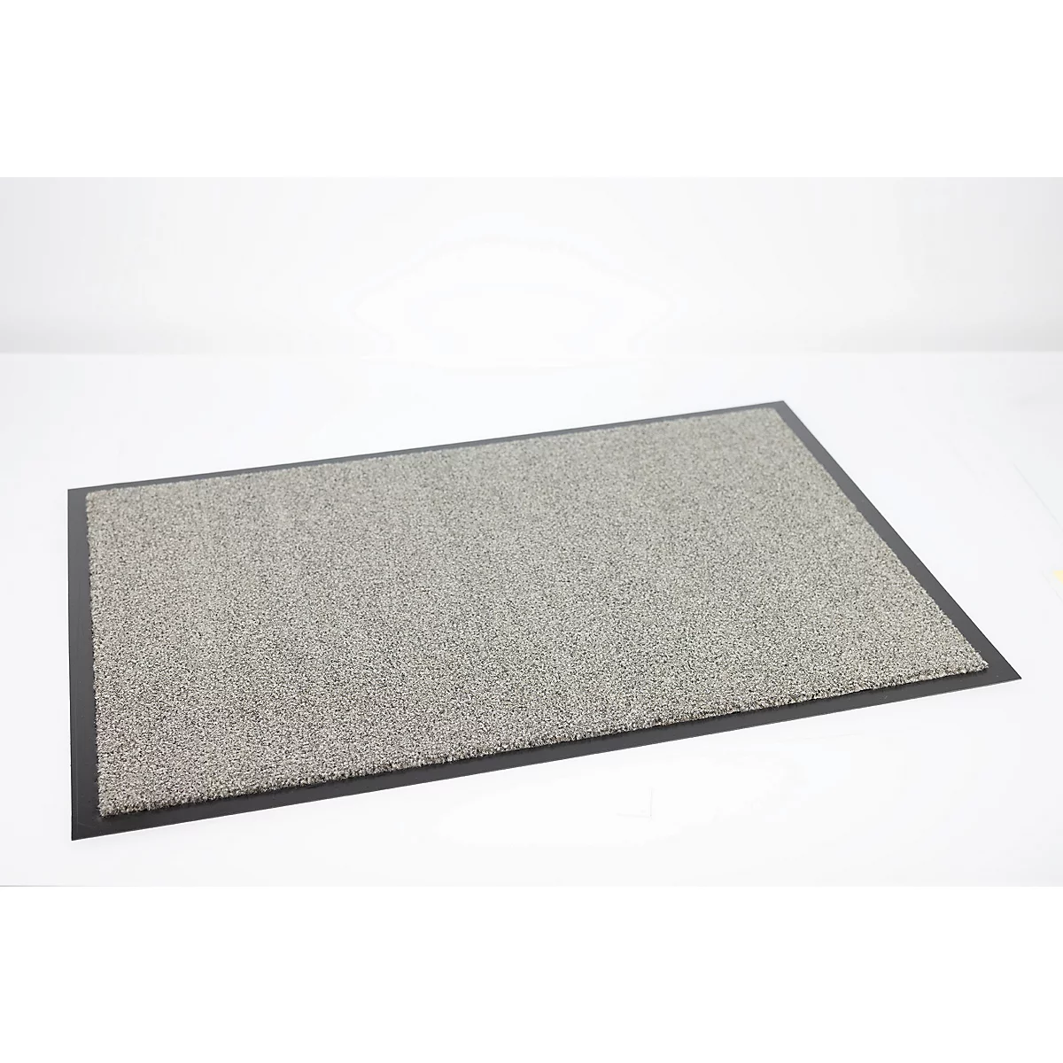 Paillasson gris rectangulaire avec bordure noire sur fond blanc neutre.