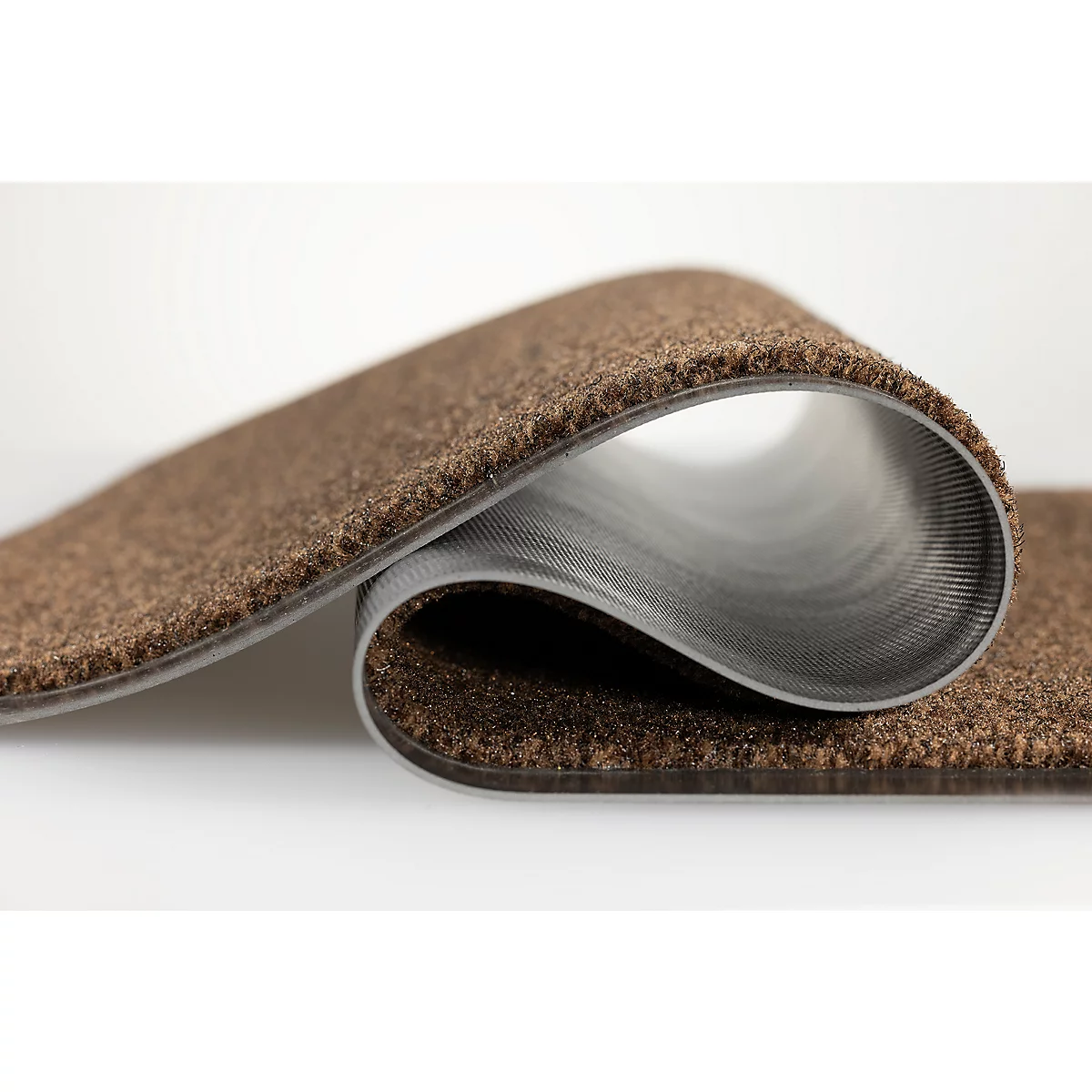 Un morceau de moquette brune incurvé montre la surface texturée et le dessous lisse et gris.