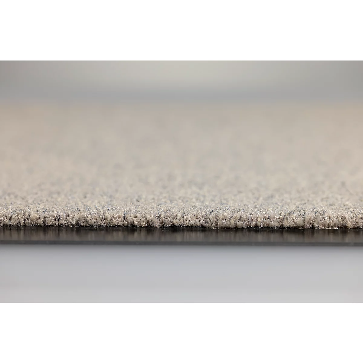 Gros plan sur le bord d'une moquette beige avec texture et sous-couche visibles.