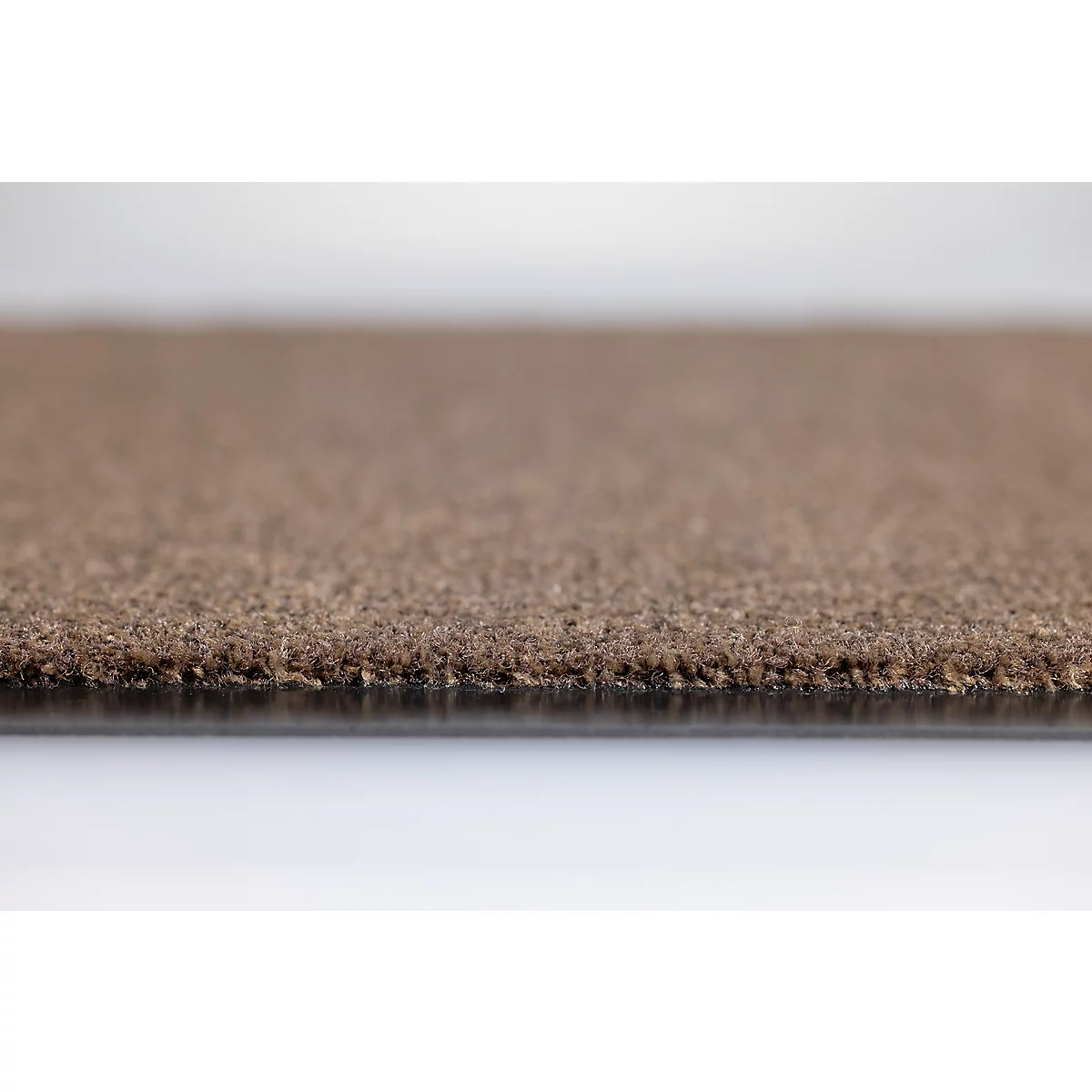 Gros plan sur le bord d'un tapis marron avec une texture visible et un matériau de support sombre.