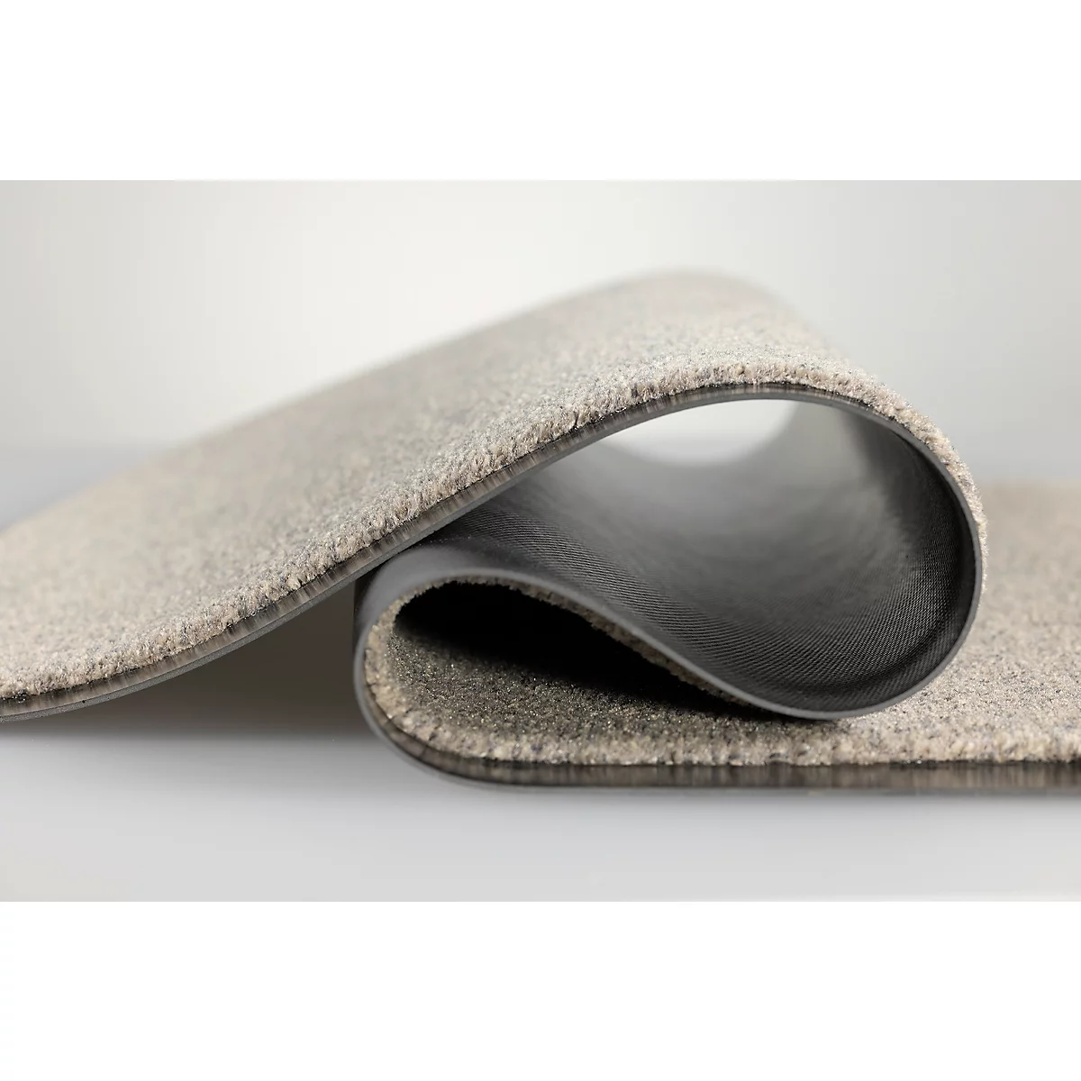 Un tapis gris avec un dos en caoutchouc foncé, se pliant élégamment.