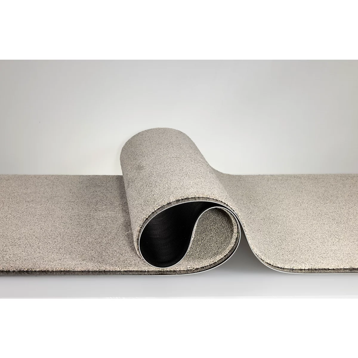 Un tapis beige enroulé avec un dessous foncé sur fond clair.