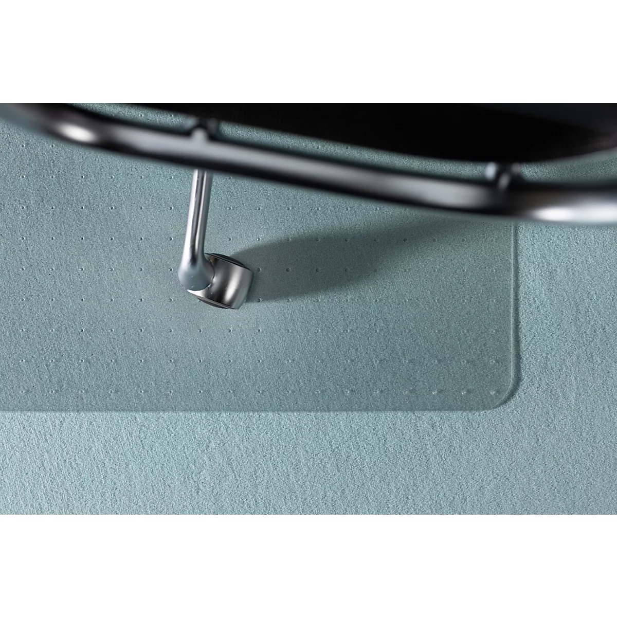Gros plan d'un tapis de protection transparent sous un pied de chaise sur un tapis bleu clair.