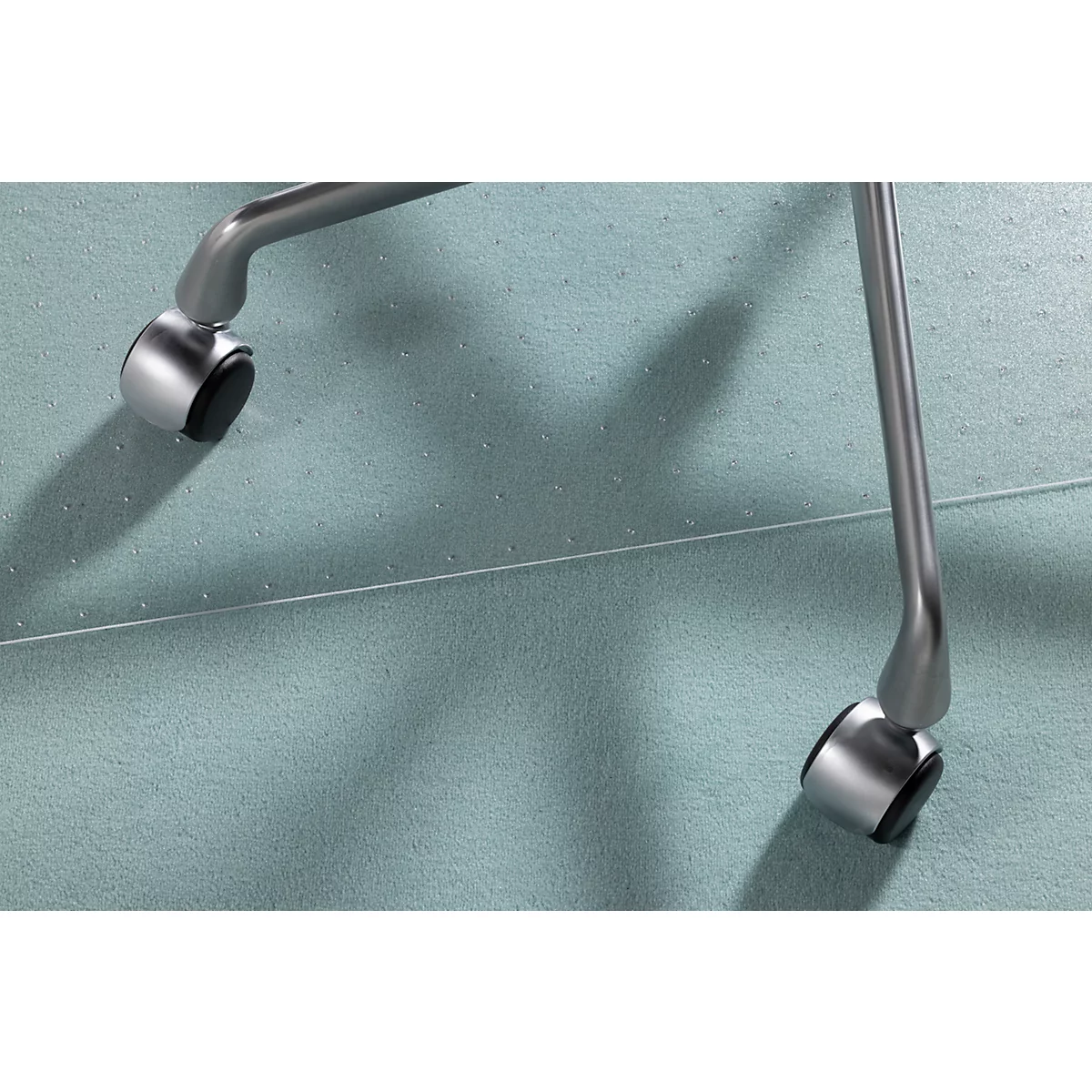 Gros plan d'une roulette de chaise de bureau argentée sur une surface bleu clair.