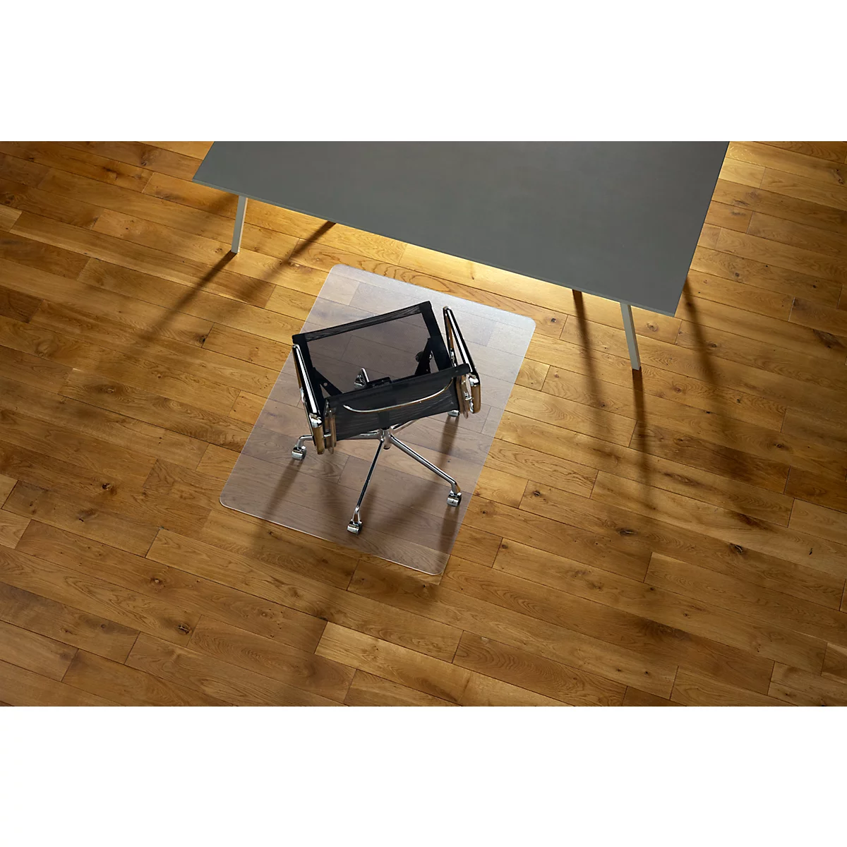 Chaise de bureau sur tapis de sol transparent sous bureau. Plancher en bois avec reflets de lumière.
