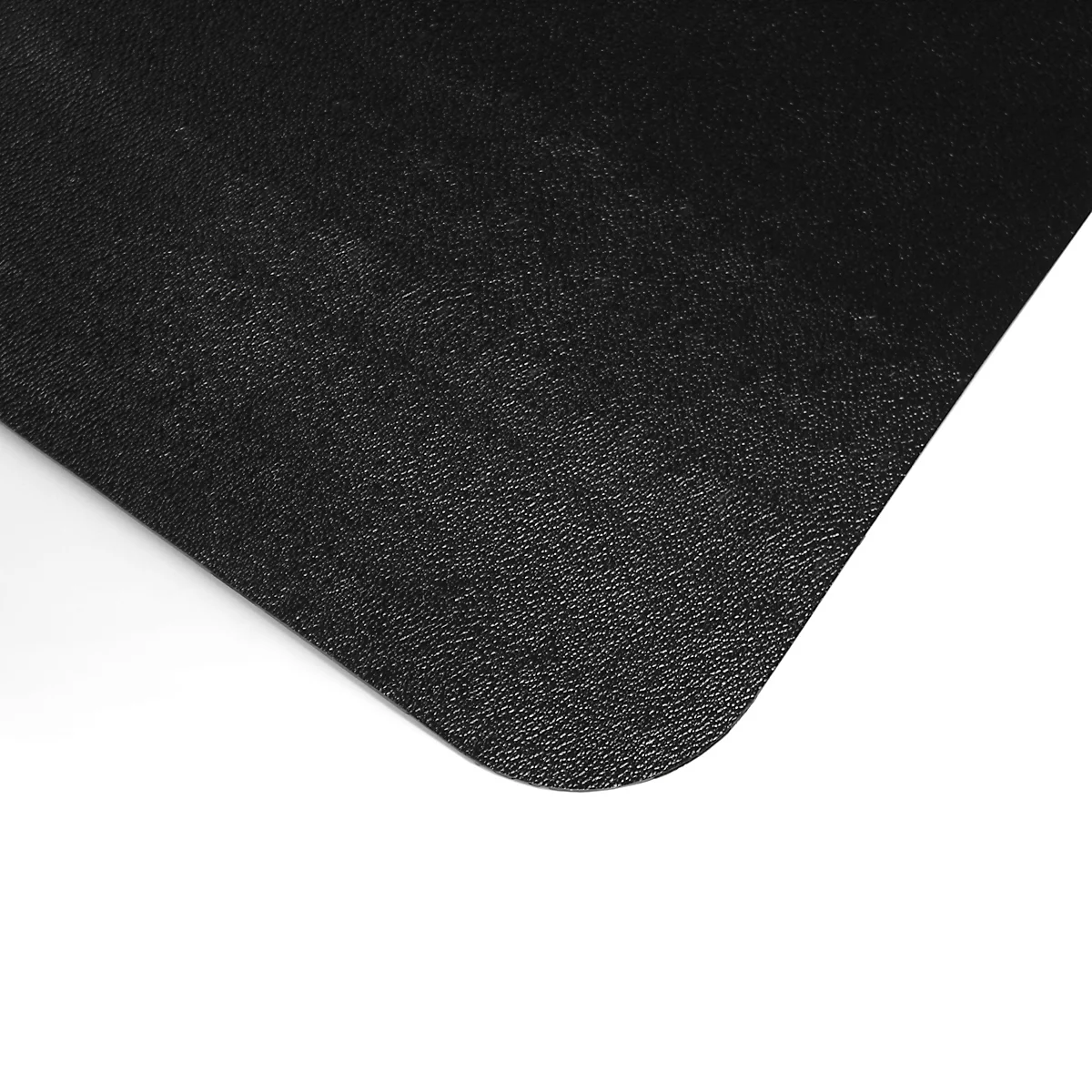 Gros plan d'un tapis noir texturé avec un coin arrondi, sur fond blanc.