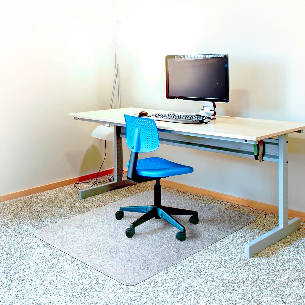 Bureau avec bureau, chaise, ordinateur et tapis de protection. Bien éclairé.