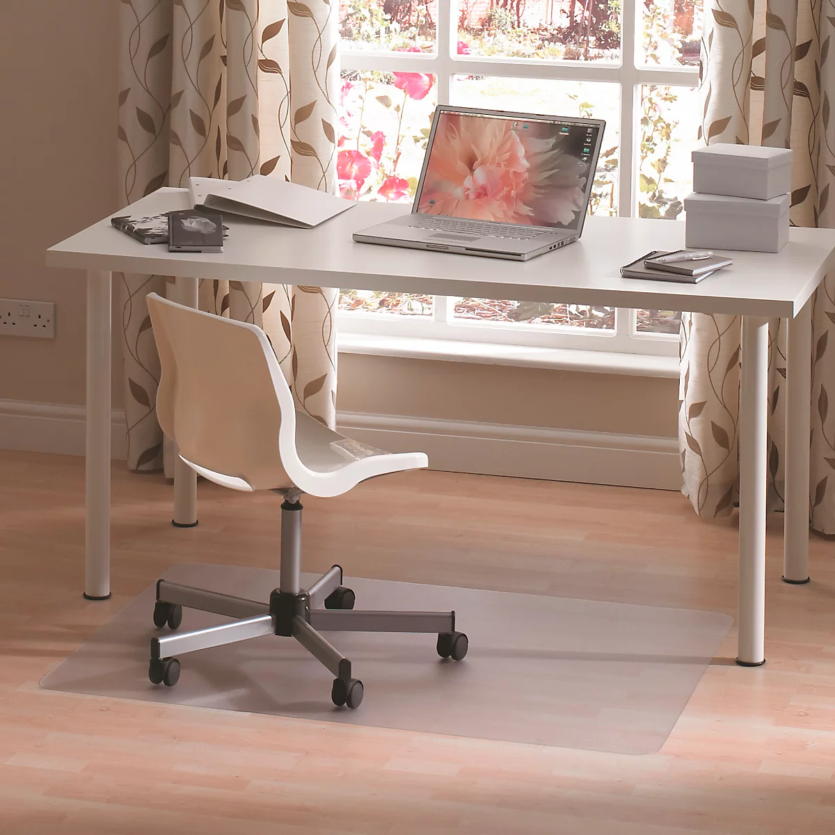 Un bureau avec un ordinateur portable, une chaise et des accessoires. Une fenêtre avec des rideaux en arrière-plan.