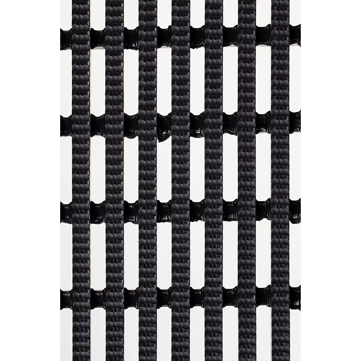 Gros plan d'un tapis noir en forme de grille avec des découpes rectangulaires régulièrement disposées.