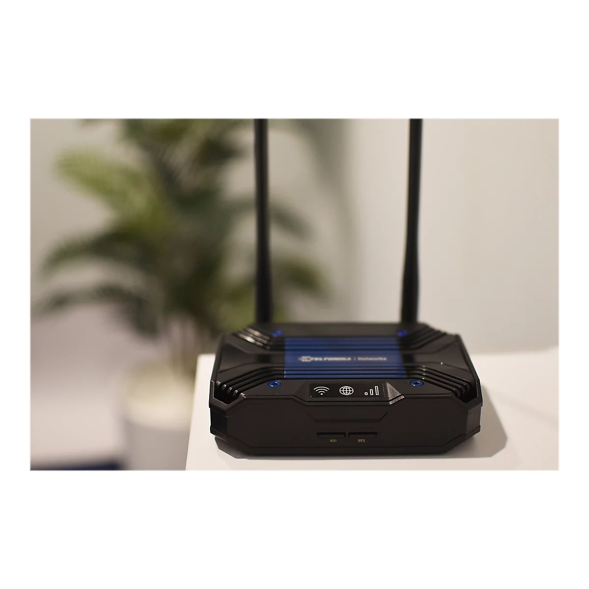 Ein schwarzer Router steht auf einem weiÃŸen Tisch. Auf der Oberseite des Routers befindet sich ein blaues Element mit weiÃŸer Schrift. Zwei Antennen ragen in die HÃ¶he.