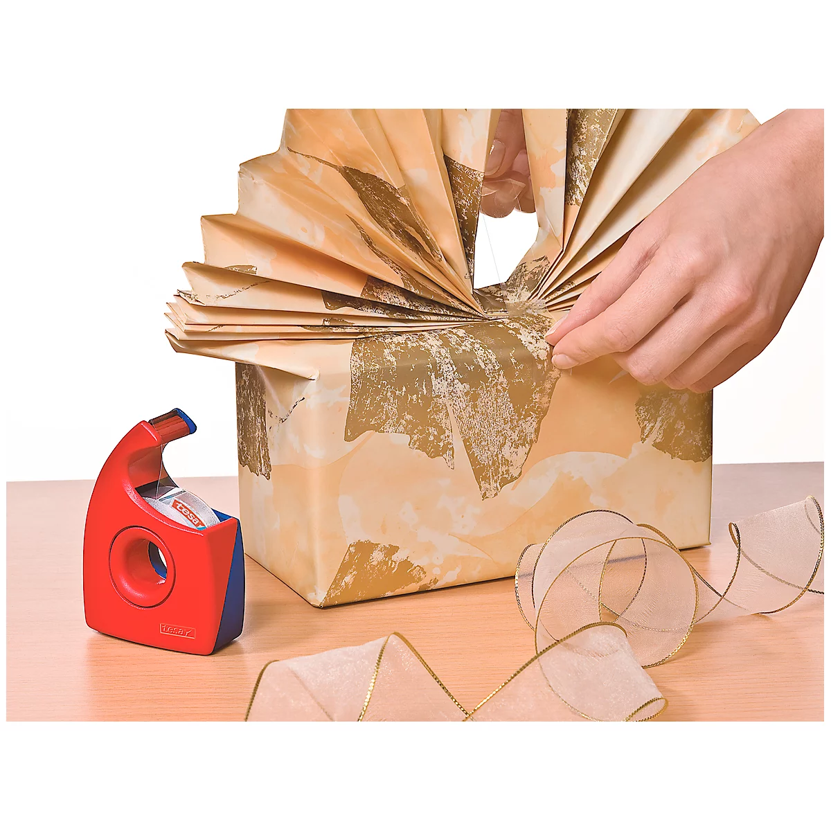 Gift being wrapped with brown paper and a ribbon. Hands hold the gift.
