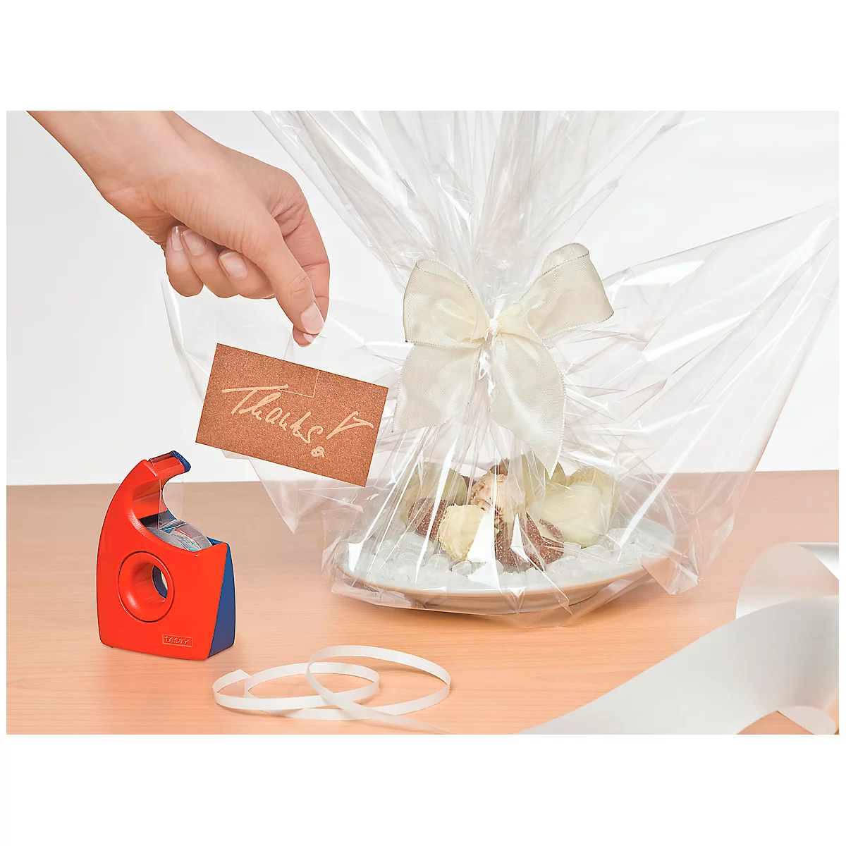 Gift wrapped in foil with bow. A thank you card is being attached.