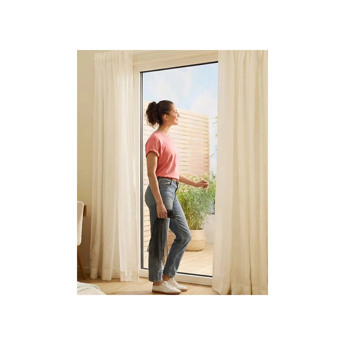 Eine Frau steht an einer offenen Terrassentür. Text: Netz aus Polyester. Schutz vor Insekten, dezenter Sichtschutz, optimale Luftzirkulation. Logo: tesa.