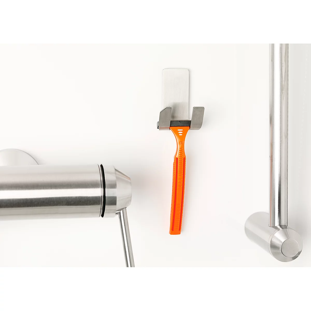 Orange razor in holder next to a towel rack, on white background.