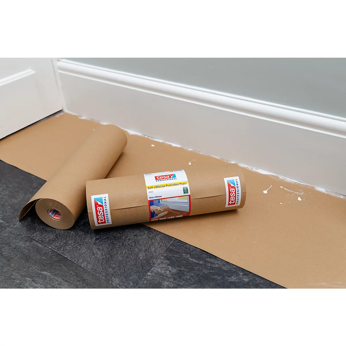 Zwei braune Papierrollen liegen auf dem Boden, eine davon abgerollt. Im Hintergrund eine weisse Wand und Sockelleiste.