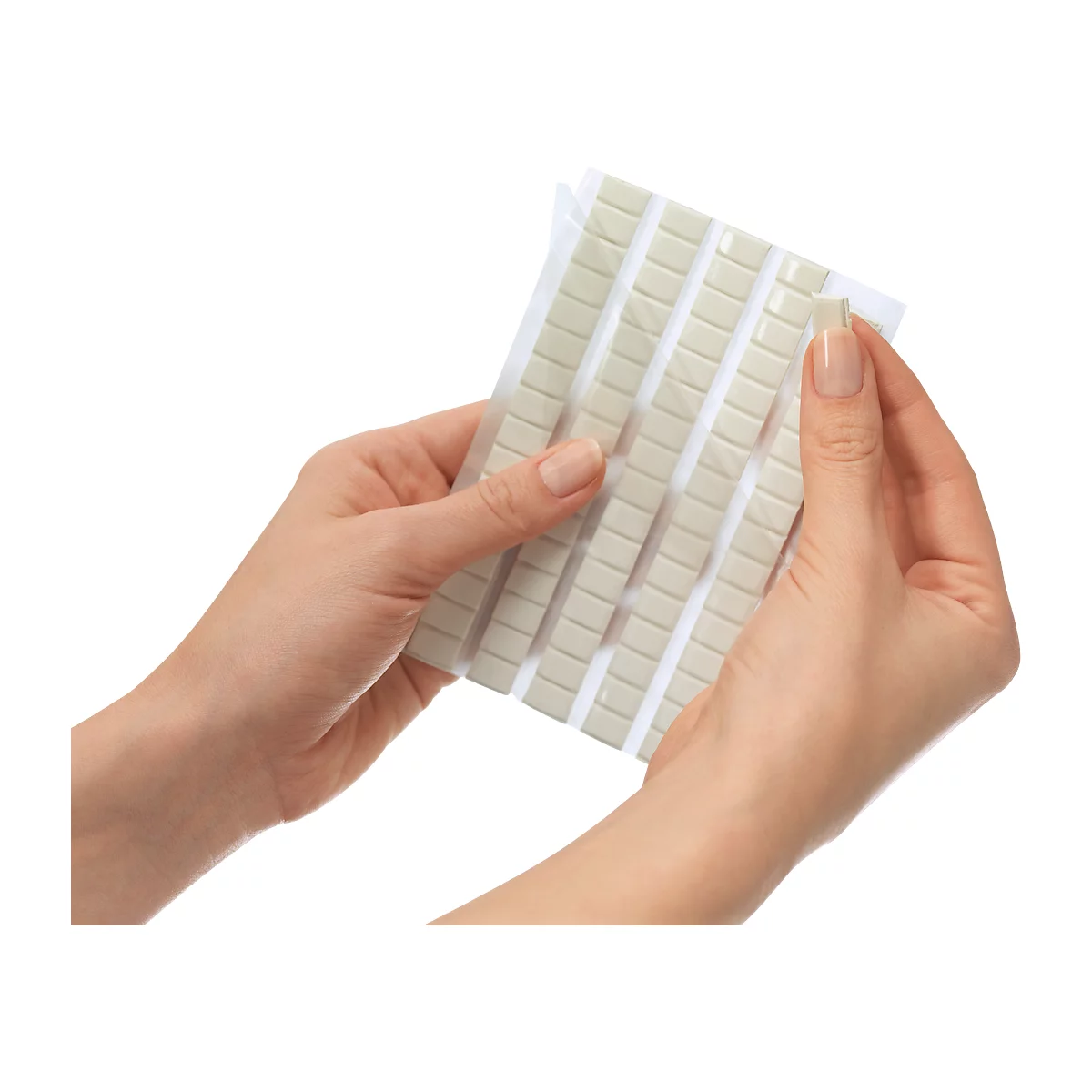 Hands holding a package of small, square adhesive pads in light gray. One pad is being removed.