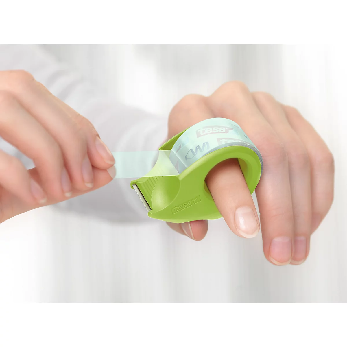 Person pulling tape from green ring dispenser attached to finger.