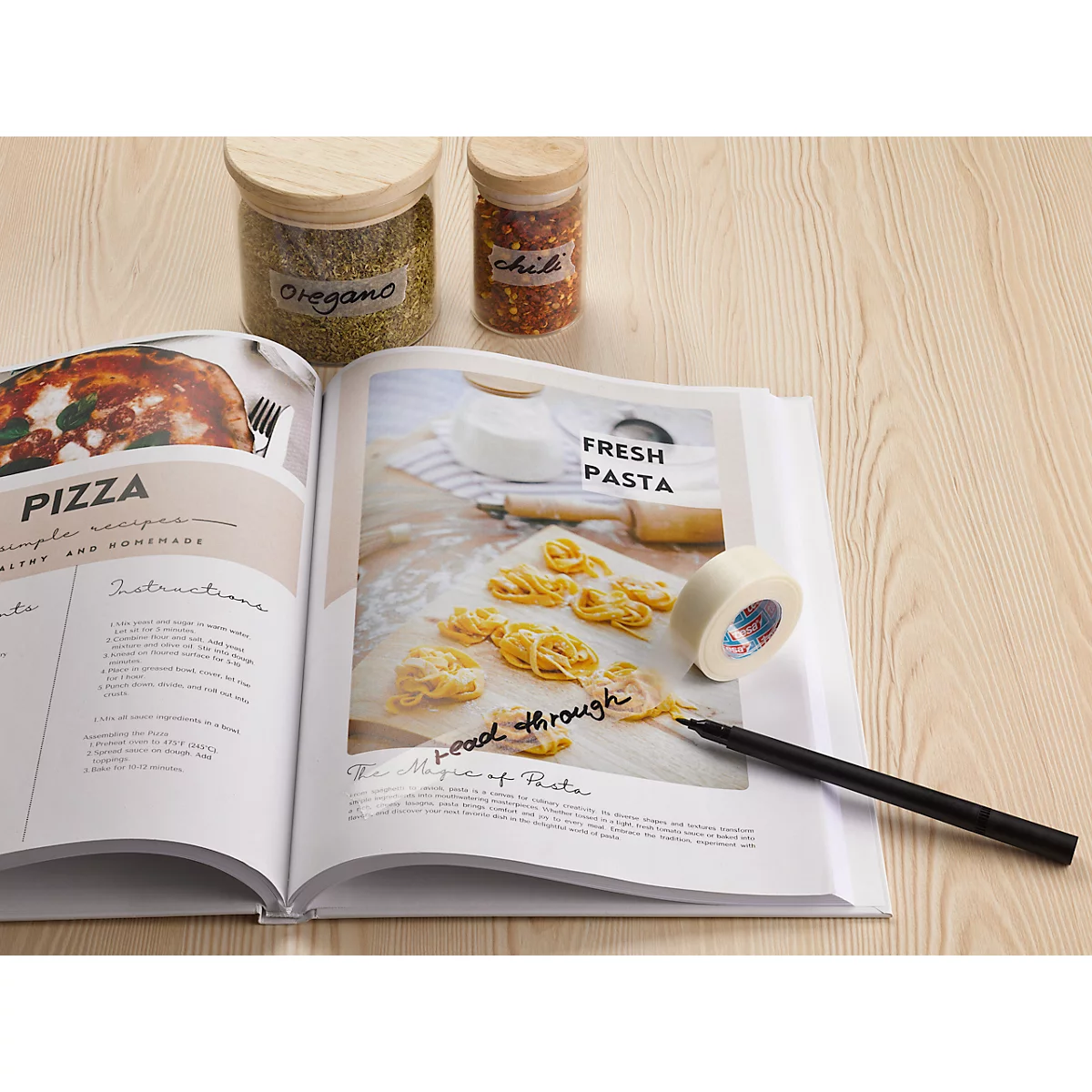 Open kookboek met pizza- en pastarecepten, naast kruidenpotjes, pen en tape.
