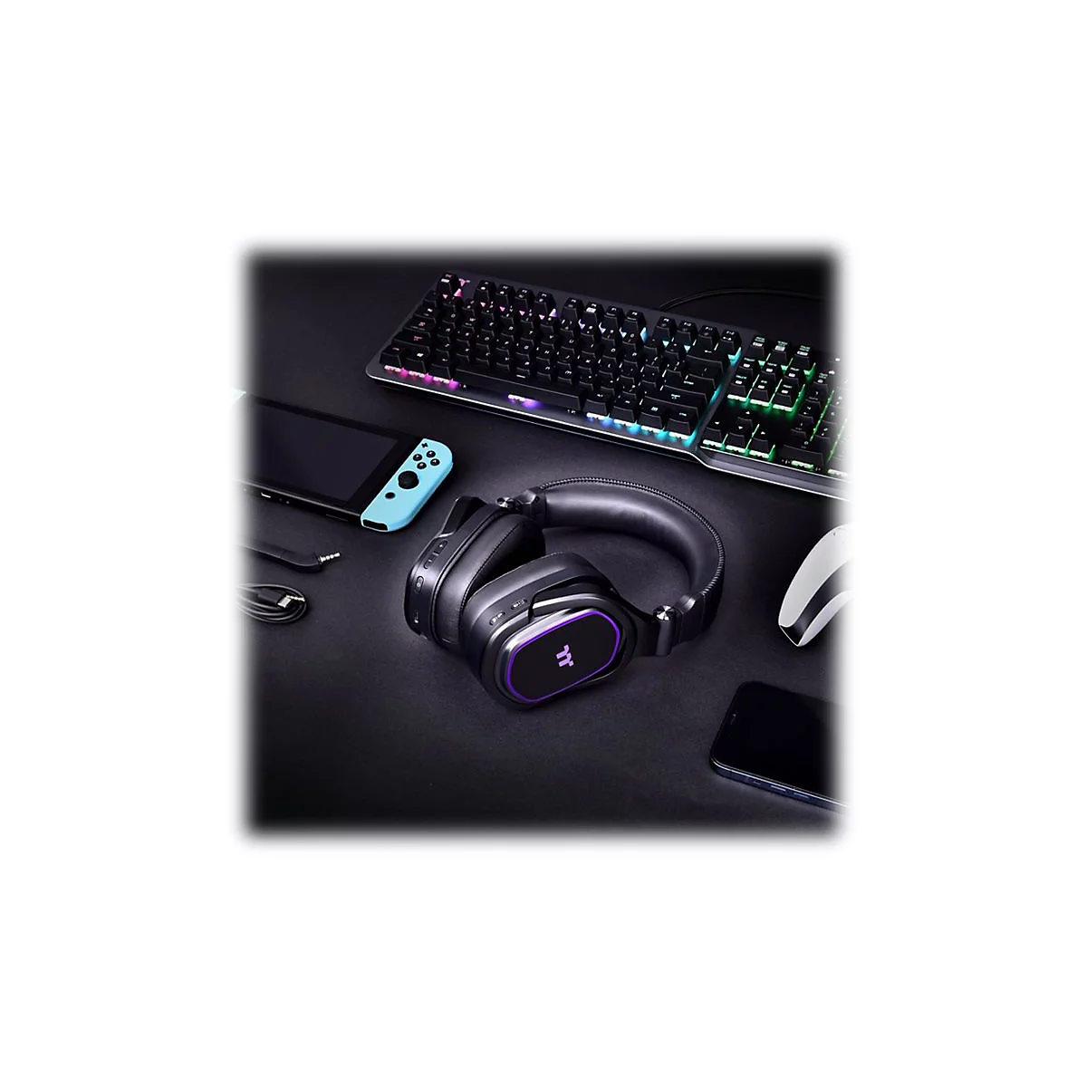 Schwarzer Gaming-Kopfhörer mit violetten Akzenten neben Switch, Tastatur und Maus auf schwarzem Grund.