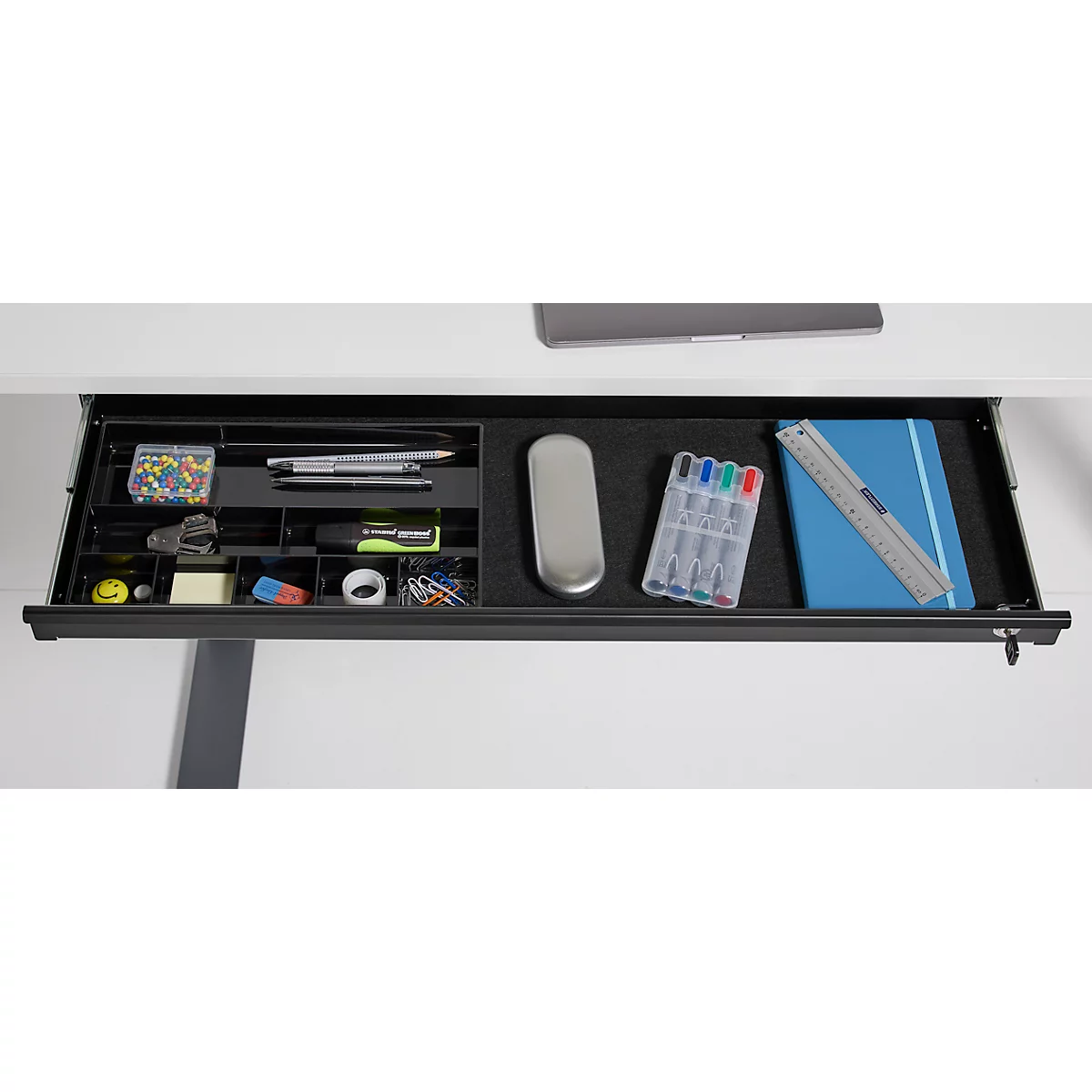 Tiroir de bureau avec fournitures d'écriture : stylos, bloc-notes, règle, trombones.