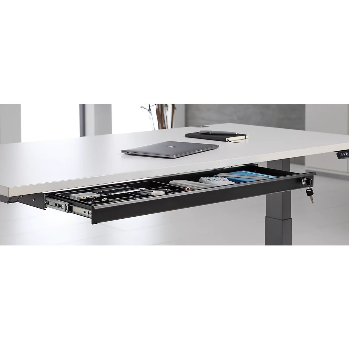 Bureau avec un tiroir ouvert contenant des fournitures de bureau.