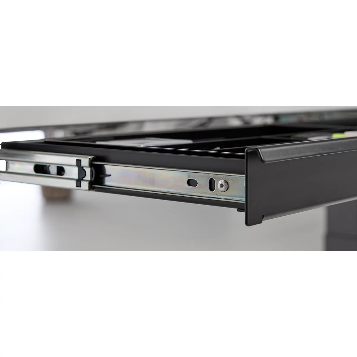 Gros plan sur un tiroir noir tiré d'un meuble, en se concentrant sur les rails métalliques.