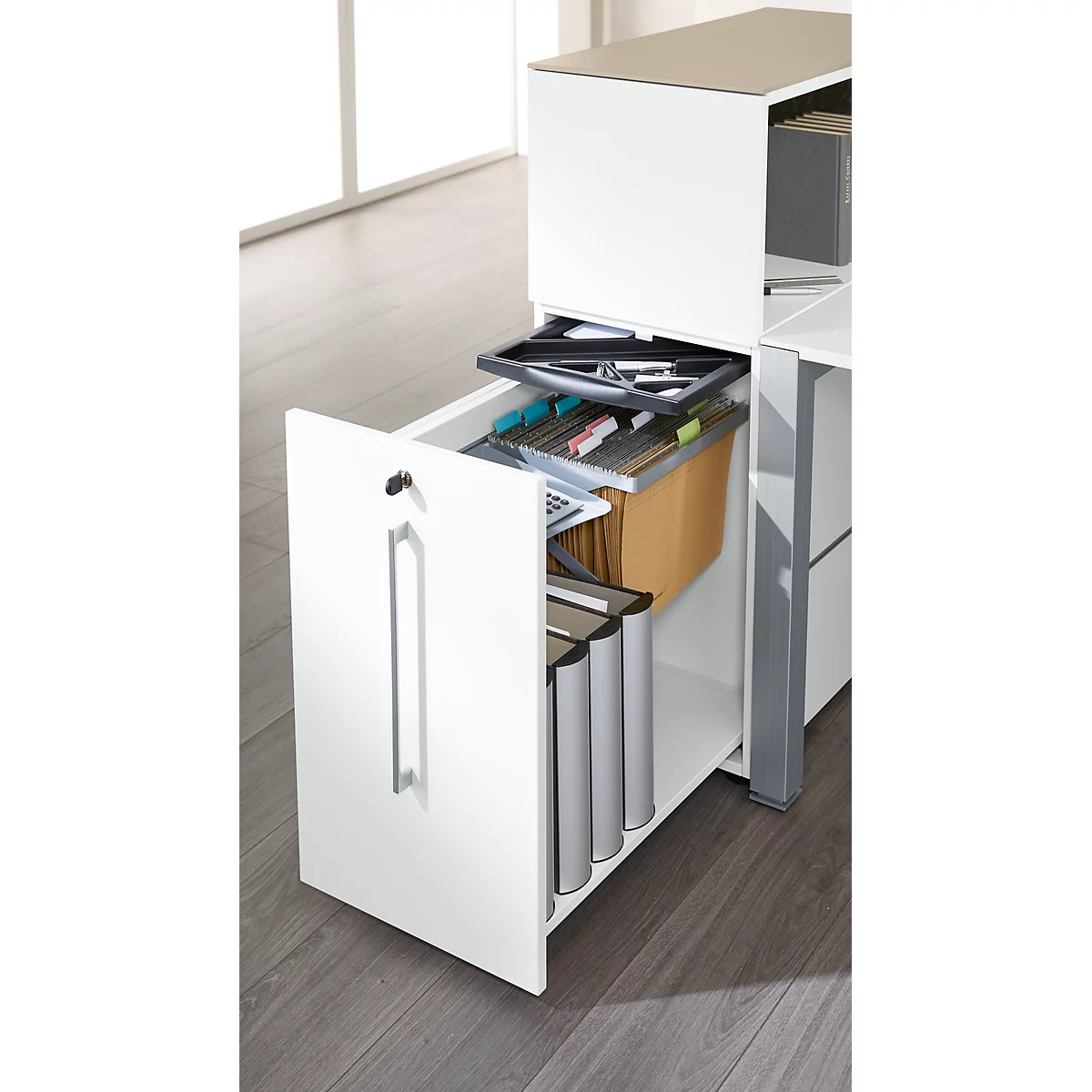 White office cabinet with an open drawer, showing file folders, pens and papers.