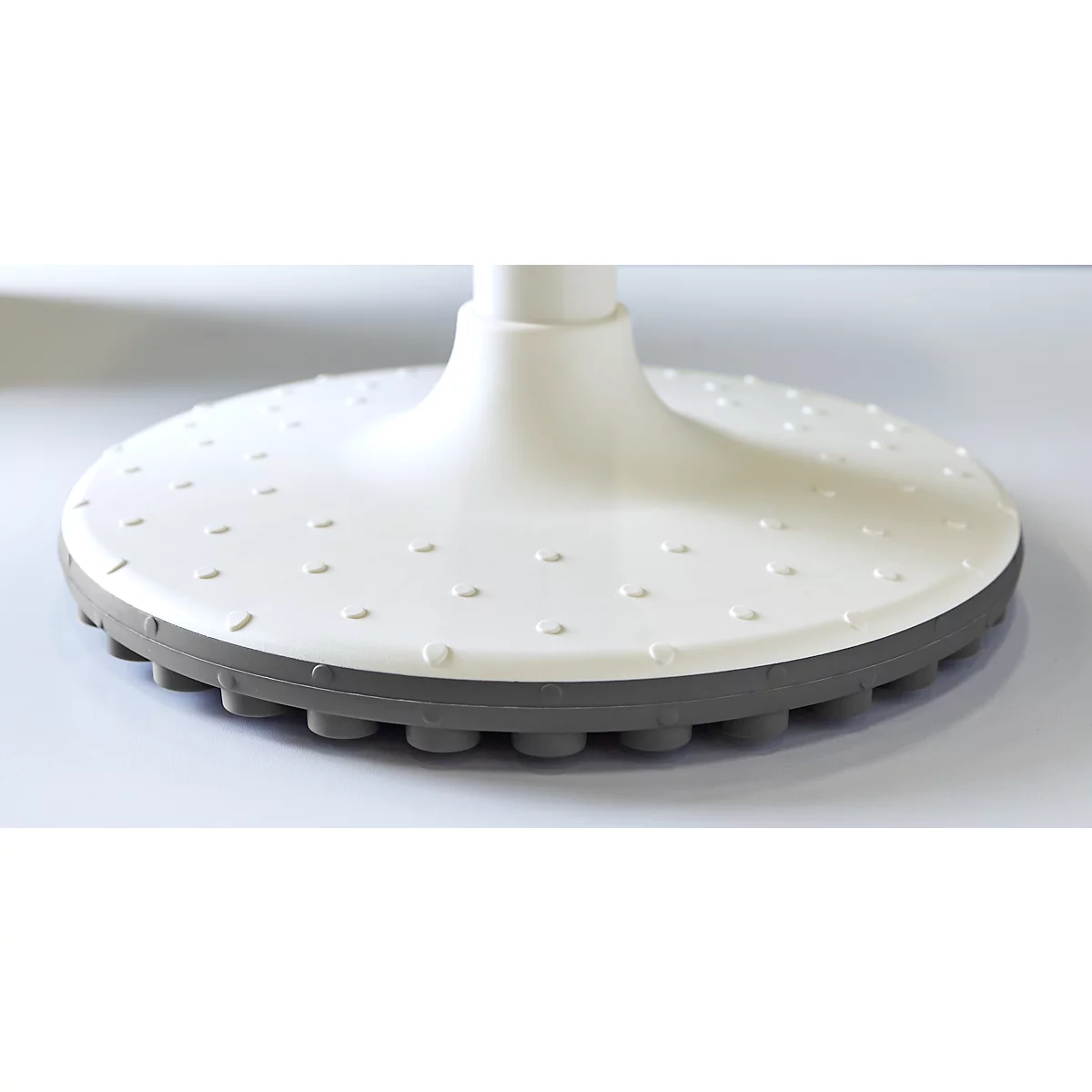 Primer plano del pie blanco y gris de una silla de oficina con protuberancias para un mejor agarre.