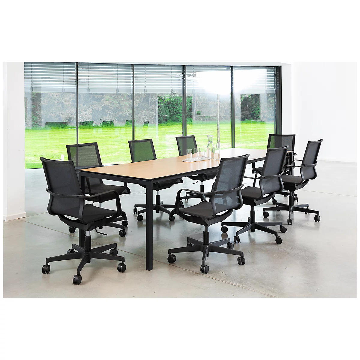 Table de conférence moderne avec huit chaises de bureau noires dans un bureau lumineux et ouvert avec une grande baie vitrée.