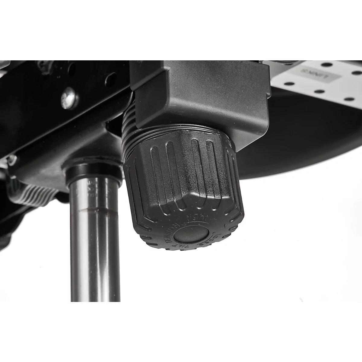 Close-up of a black rotary knob on an office chair. The knob is knurled and attached to a metal structure.