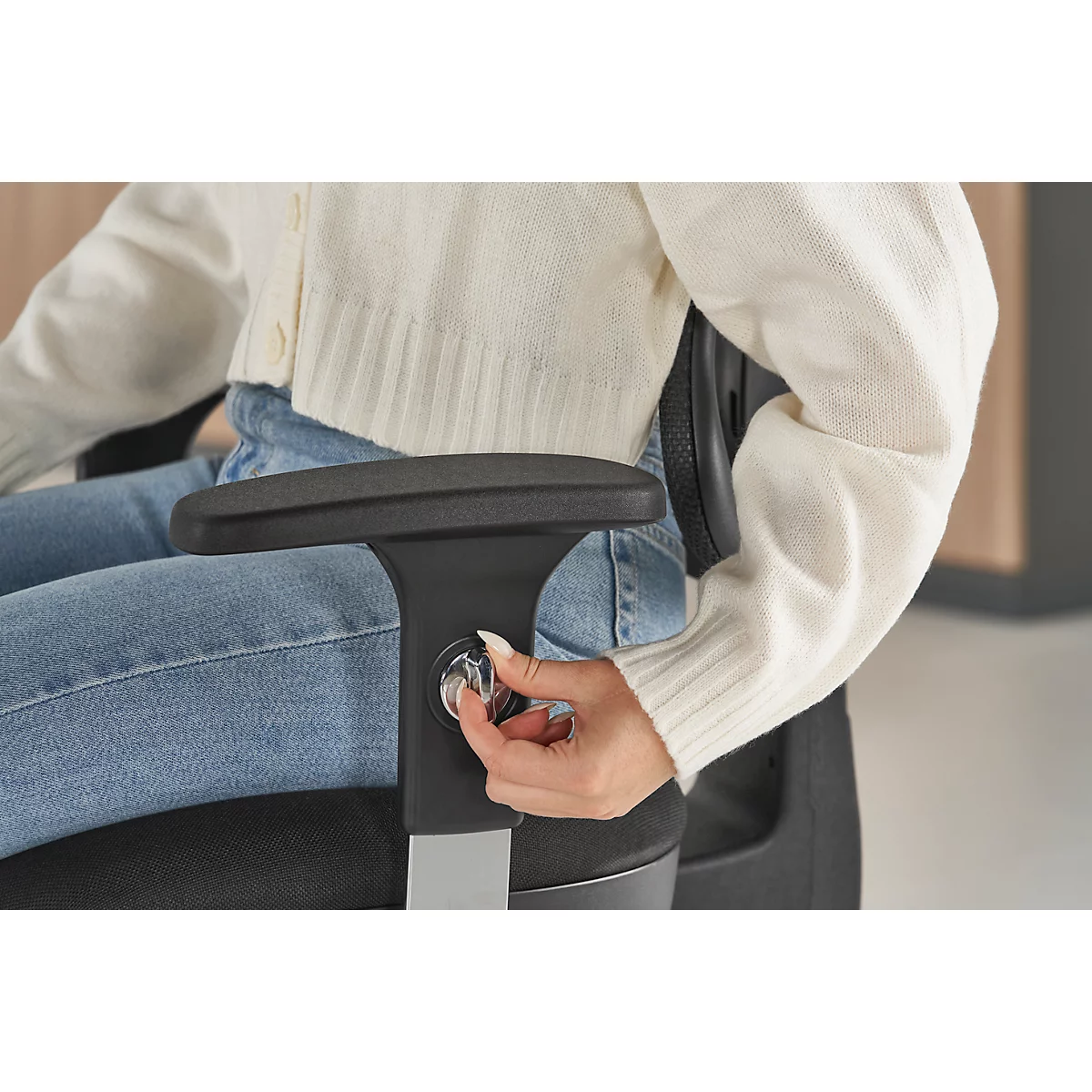 Close-up of a person adjusting the height of a black office chair.