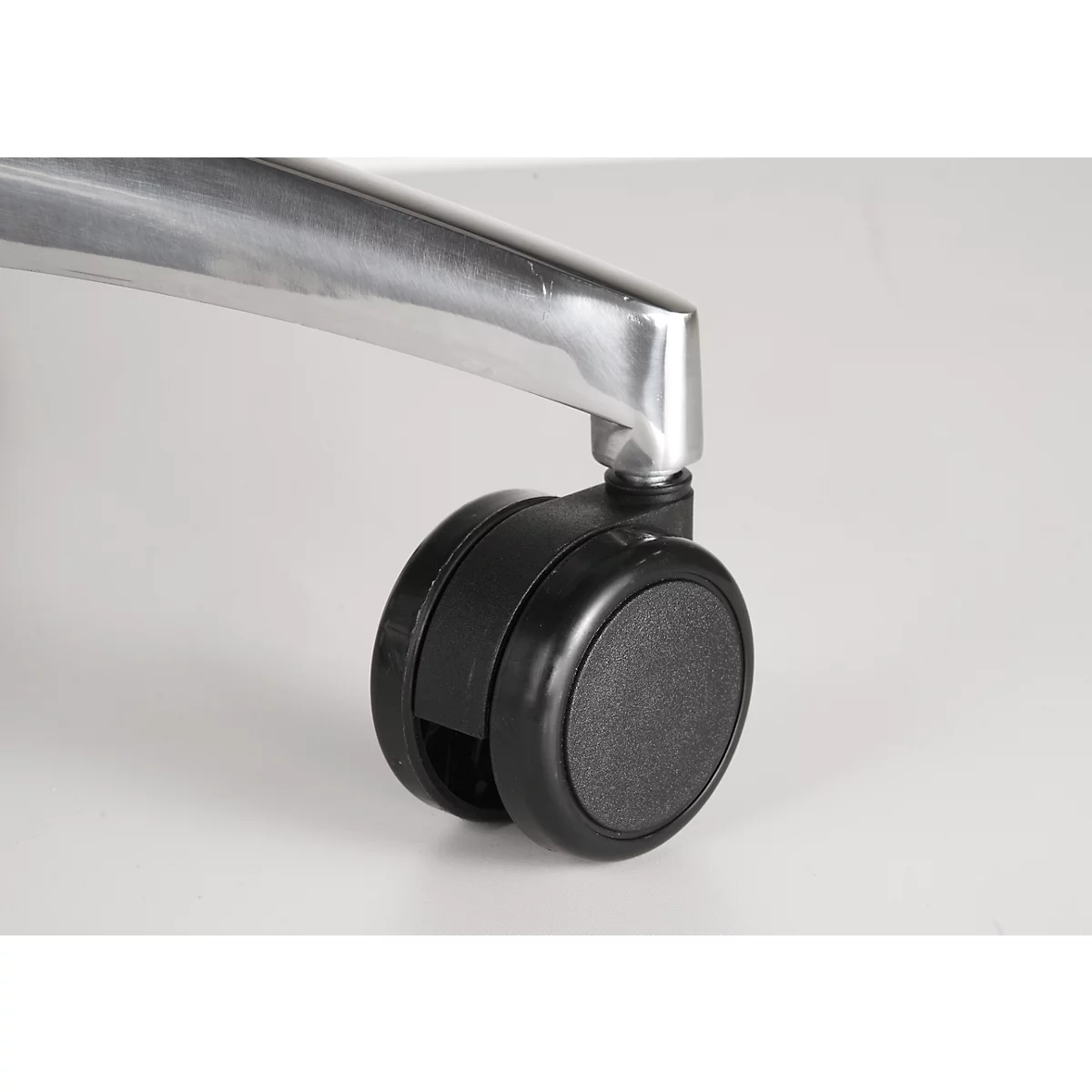 Close-up of a black double caster under a silver office chair leg.